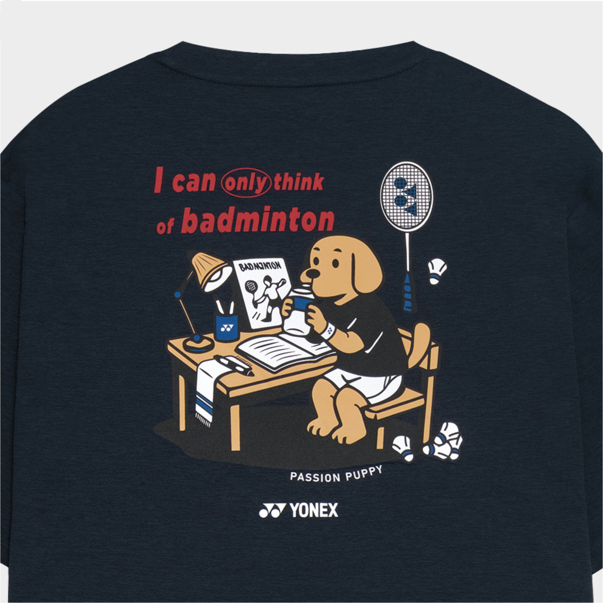 Navy blue t-shirt with cartoon dog and badminton-themed design, featuring Yonex logo.