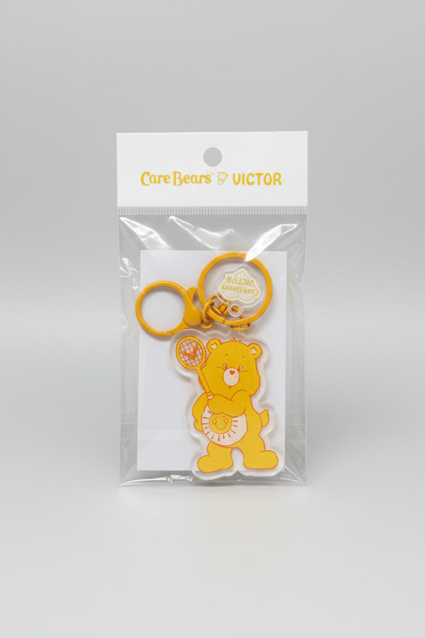 Packaged yellow keychain with teddy bear design on a black background
